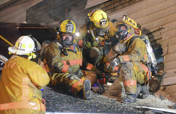 Exhausted Lisbon firefighters take a quick break as they talk with Assistant Chief Kurt Gresh about the stubborn fire in the roof.
  (Patricia Schaeffer / The (Lisbon) Morning Journal)